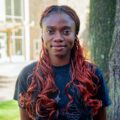 Young woman with black red poses for her photo wearing a black shirt. Photo captured by Jaden Mezetin Photography.