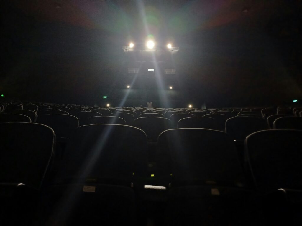 Darkly lit theater with three spot lights shining at camera. Image curtesy, Unsplash.